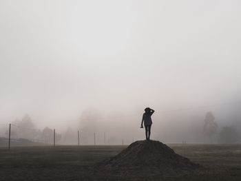 Rear view of man standing on field in foggy weather