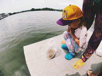 Fish-eye lens shot of curious girl looking at frogs in plastic bag by lake