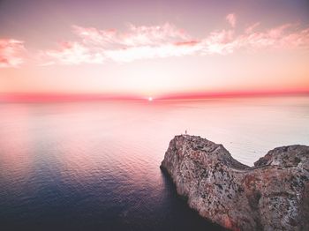 Majestic seascape with distant lighthouse on rocky coastline