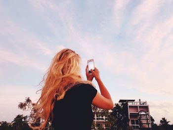 Rear view of woman photographing against sky