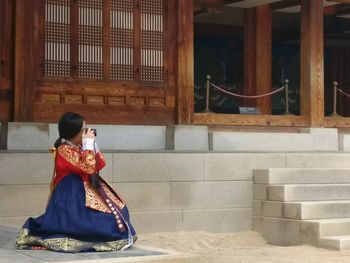 Side view of woman sitting outdoors