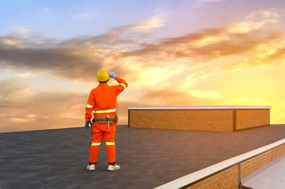 Man standing by sea against sky during sunset