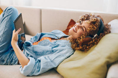 Side view of woman using mobile phone while lying on bed at home