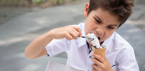 Cute child boy with a dirty face eats ice cream, the child enjoys dessert