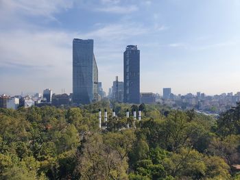 Trees and buildings against sky in city