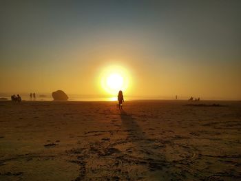 Silhouette man on beach against sky during sunset