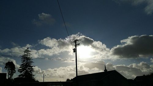 Low angle view of silhouette electricity pylon against sky