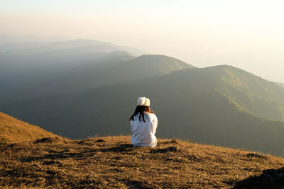 Rear view of woman looking at mountains against sky