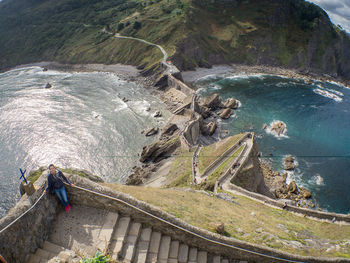 High angle view of rocks by sea against mountain in the spanish island of gaztelugatxe