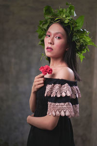 Portrait of a beautiful young woman standing by flower