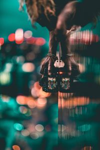 Close-up of man photographing while standing by wall in city at night