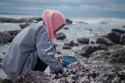 Woman collecting rocks on beach