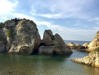 Rock formation in sea against sky