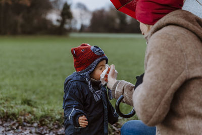 Midsection of mother and son standing on field during winter