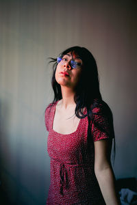 Young woman standing against wall