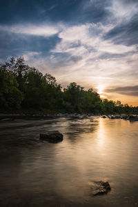 Scenic view of river against sky at sunset
