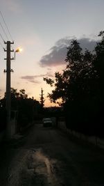 Cars on street against sky at sunset