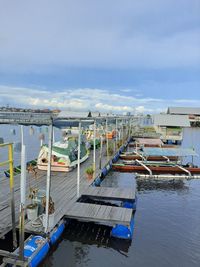 Boats moored at harbor against sky