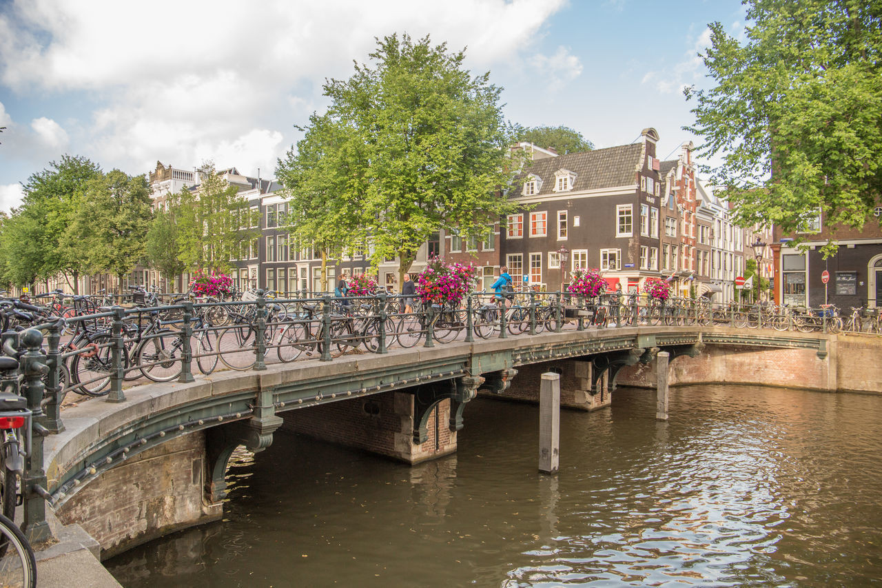 BRIDGE OVER CANAL AMIDST BUILDINGS IN CITY