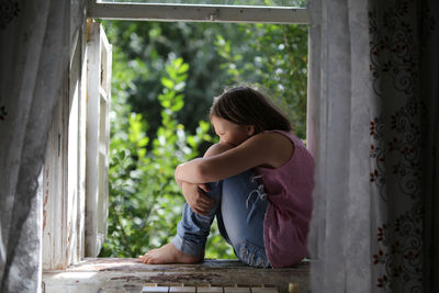 Child girl on the window, the concept of sadness and loneliness, the problems of childhood