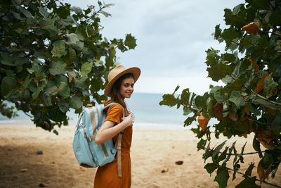 Portrait of young woman standing by tree