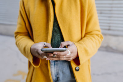 Woman using mobile phone against wall