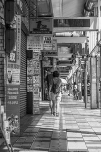 Rear view of woman walking on sidewalk