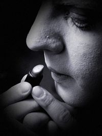 Close-up of man holding cigarette against black background