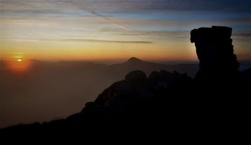 Scenic view of silhouette mountains against orange sky