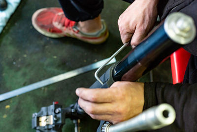 Low section of man sitting while holding fishing rod