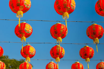 Low angle view of red lanterns hanging against blue sky