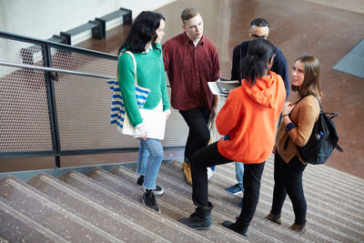 Male and female students talking while standing on steps in university