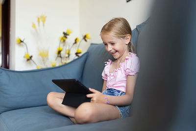 Side view of woman using laptop while sitting on sofa at home