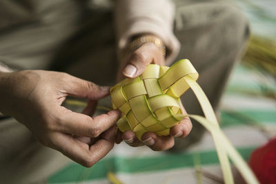 Weaving the coconut leaves making the ketupat, a traditional malay cuisine for the eid celebration.