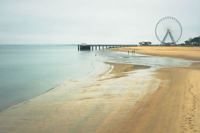 Scenic view of beach and ferris wheel against sky