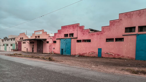 Empty road amidst buildings against sky