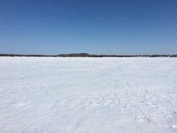 Surface level of frozen lake against clear blue sky