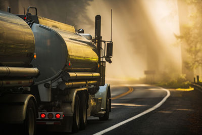 Semi tank truck transporting fuel on the scenic redwood highway during foggy morning scenery. 