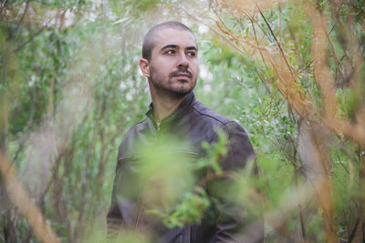 Portrait of young man standing against trees