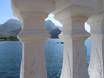 Close-up of sea by mountain against sky