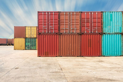 Stack of multi colored cargo containers at harbor against sky