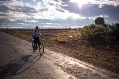 Rear view of man riding bicycle on street