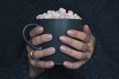 Cropped hands of woman holding marshmallows in mug