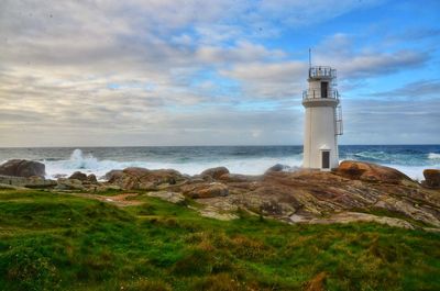 Lighthouse by sea against sky during sunset