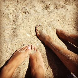 Low section of woman and man on sand at beach