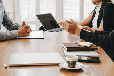 Midsection of woman using laptop on table