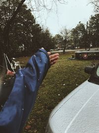 Low section of man on car against sky