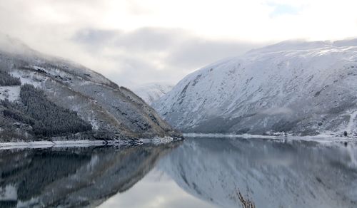 Scenic view of lake by snowcapped mountains against sky