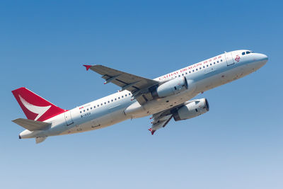 Low angle view of airplane flying against clear blue sky