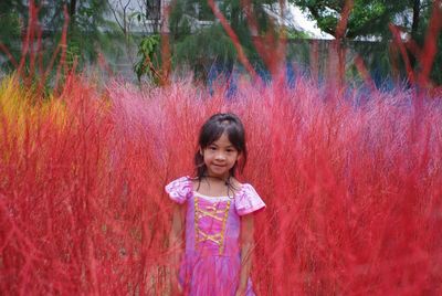 Portrait of a smiling girl standing against pink plants